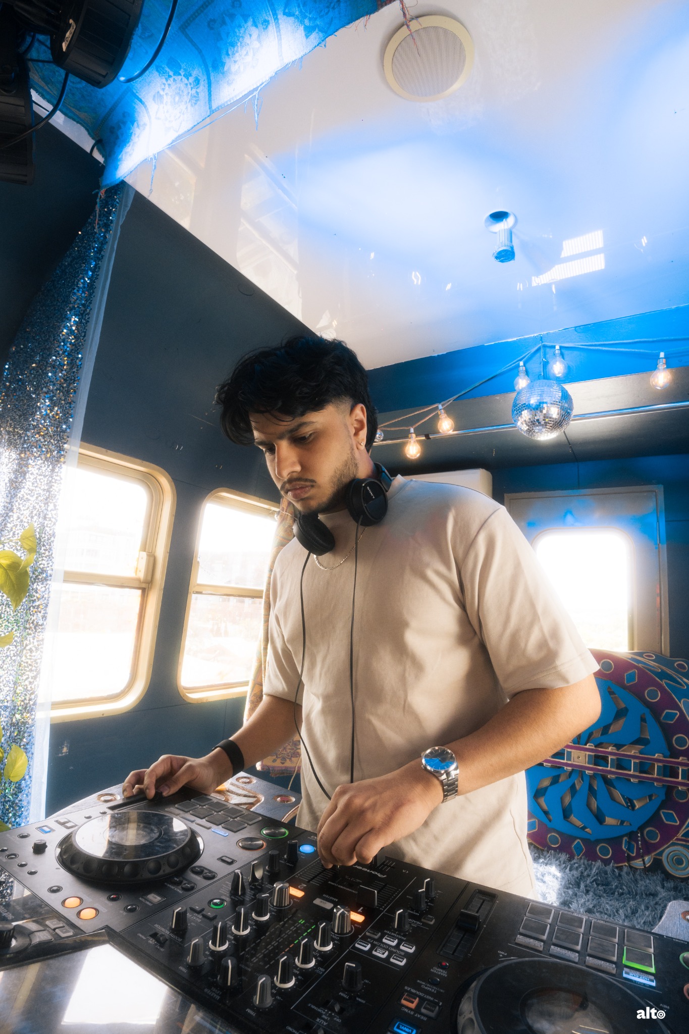 YUVI DJing in a bright room with disco ball lighting